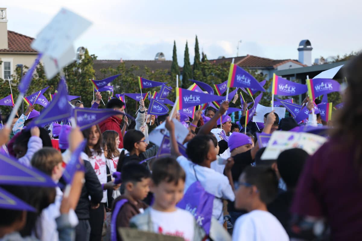Alameda Post - A group of elementary students wave purple flags in the air. 