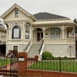 Alameda Post - the home at 1290 Weber, a very well kept yellow home with a bright green lawn and a fence