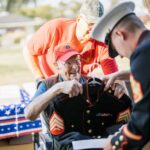 Alameda Post - Bill Darling smiles broadly while being presented with Dress Blues by a younger Marine