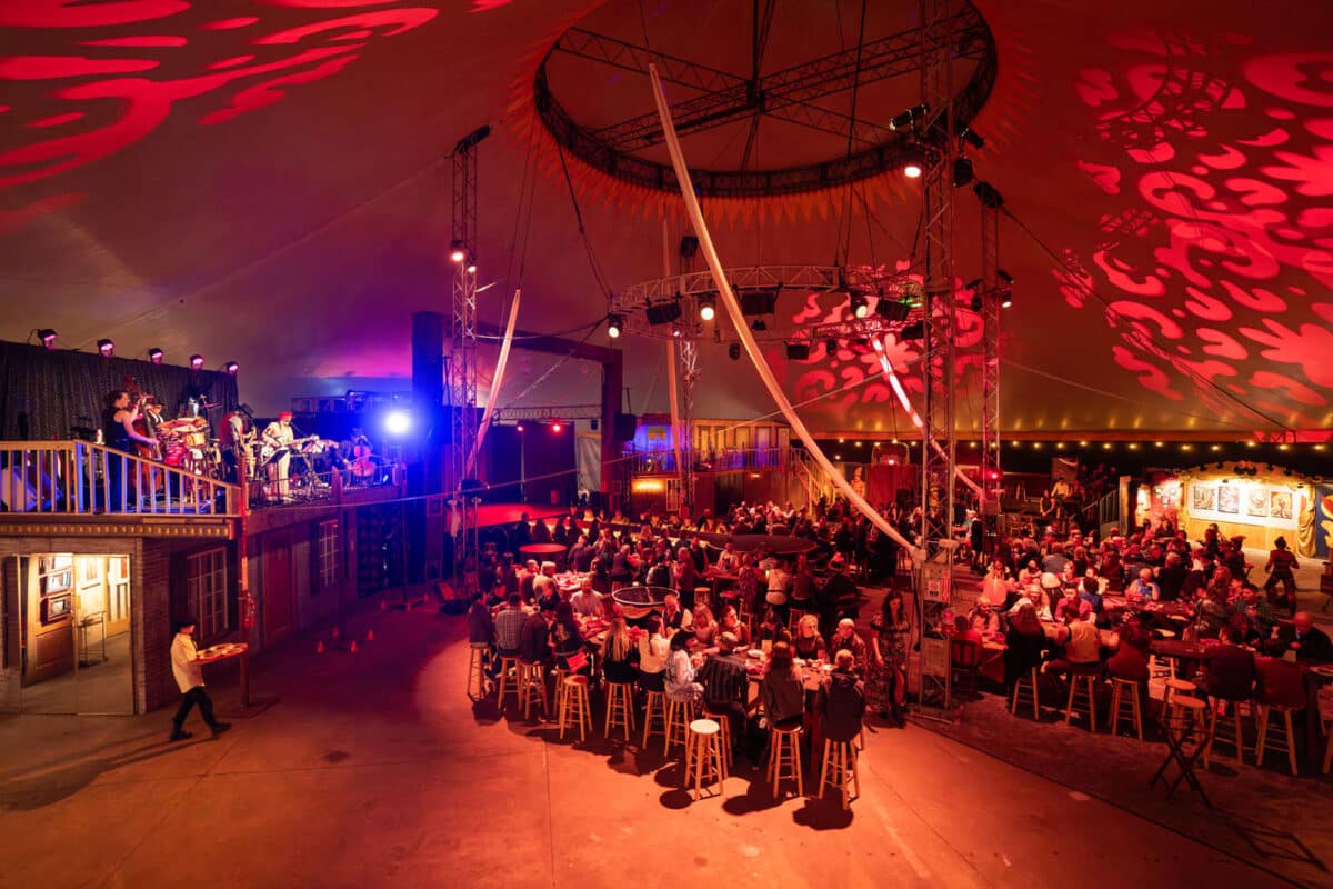 Alameda Post - the interior of the Soiled Dove circus tent with lots of tables, performances areas, and a stage