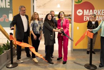 Alameda Post - Local leaders smile and hold a huge pair of scissors at the ribbon cutting of the Alameda Food Bank.