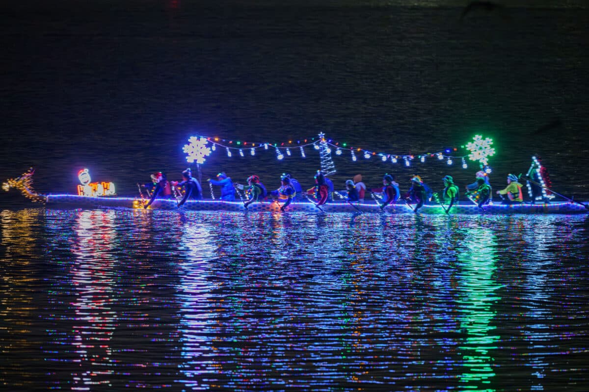 Alameda Post - A dragon boat with holiday lights paddles on the water at night.
