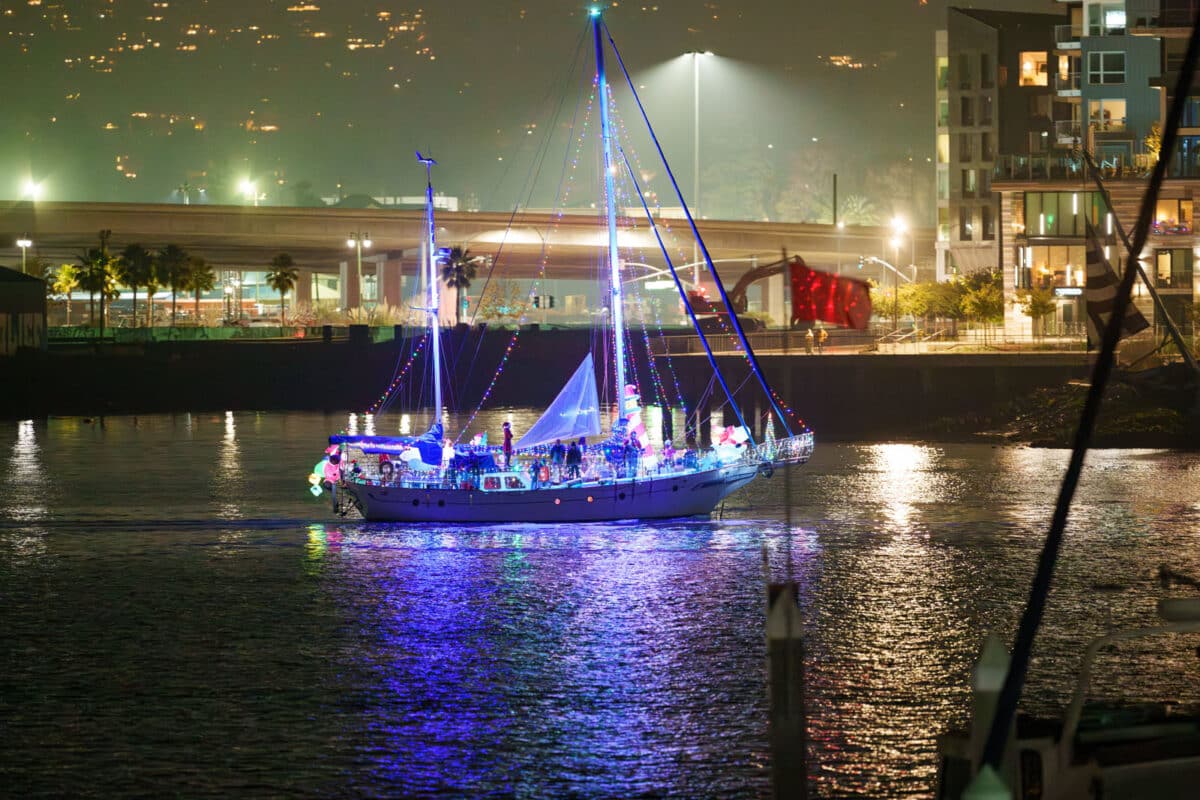 Alameda Post - a Sail boat with Christmas lights sails past.