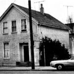 Alameda Post - a structure at 2320 Lincoln Avenue in a black and white photo. The structure is a modest, wooden, two story building with a door and four small windows