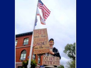 Alameda Post - a man stands in front of Alameda City Hall with signs that say "Trump and his corrupt (Nazi) Cabinet are the true terrorists. Do not be intimidated."