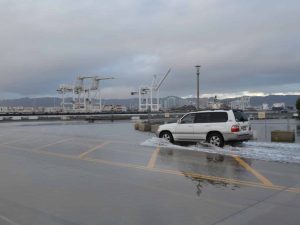 Alameda Post - A white SUV makes waves as they drive through water at Alameda Point.