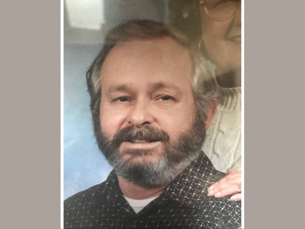 Alameda Post - James Gary Stutler smiles in a photograph. A woman that appears to be close to his age stands behind him and smiles.