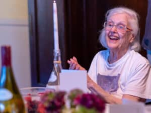Alameda Post - An older Patricia Ferris Millosovich with white hair smiles at the dinner table.