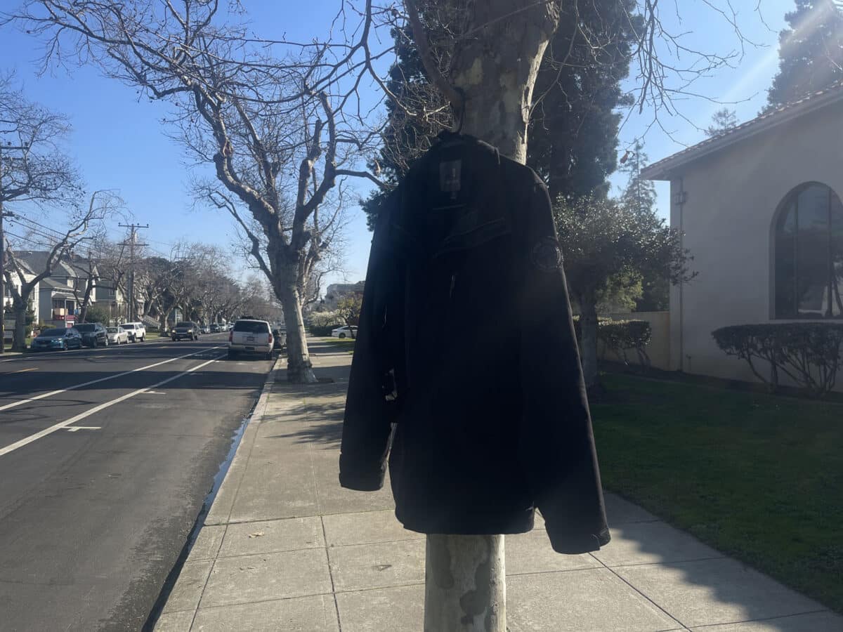 Alameda Post - A coat hung out on a hanger on a tree.