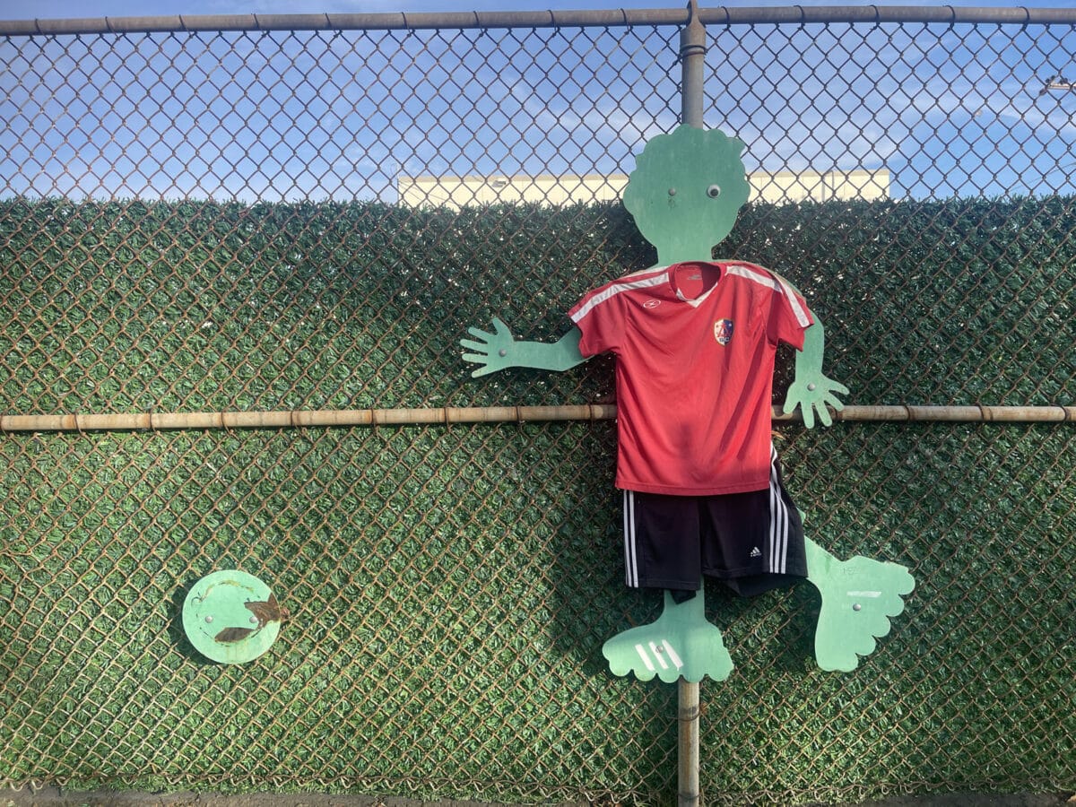 Alameda Post - A decoration of a cutout figure of a child kicking a soccer ball. The cutout is wearing a jersey.