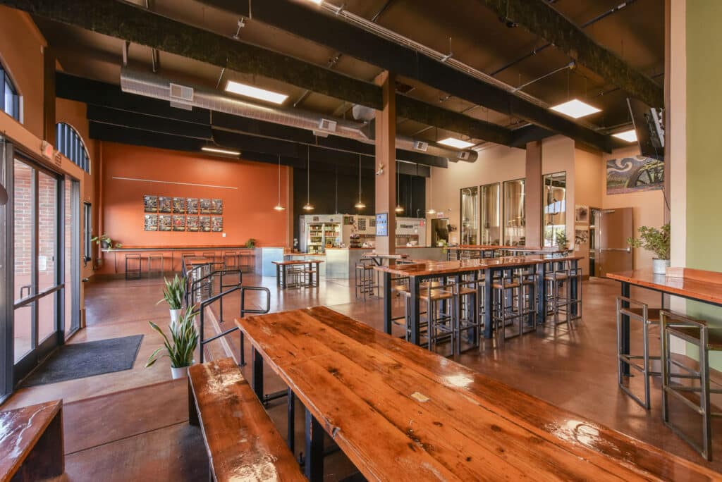 Alameda Post - the inside of Alameda Brewing's taproom. Lots of shining wooden tables and metal accepts decorate the open and well-let space