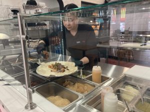 Alameda Post - behind the counter at Taco Fino, a worker prepares a burrito