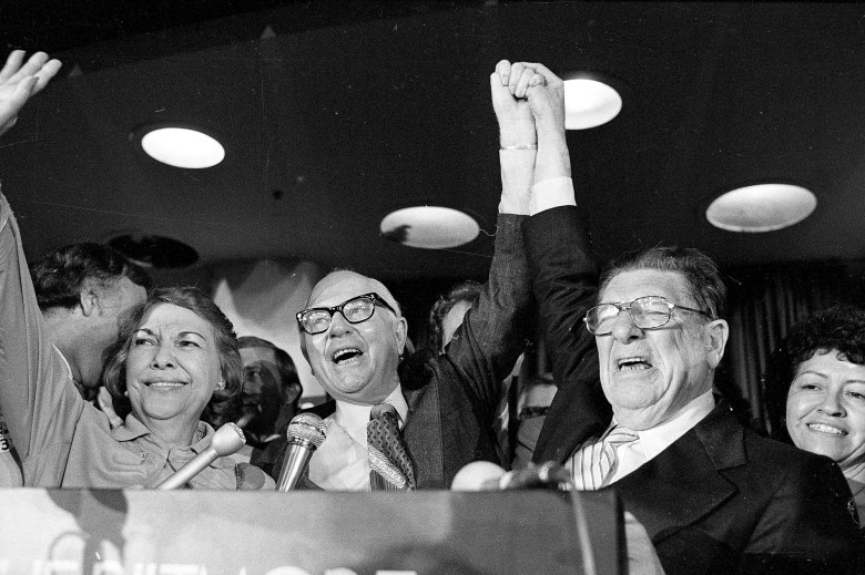 Paul Gann, left, and Howard Jarvis hold up their hands as their co-authored initiative Propsition 13 takes a commanding lead in the California primary, in Los Angeles, June 7, 1978. Photo by AP Photo