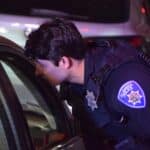 Alameda Post - An APD officer leans over to speak to somebody out of frame in a car.