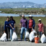 Alameda Post - five volunteers hold trash bags and smile