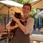 Alameda Post - Baby the Cat in the arms of a member of waitstaff at Julie's