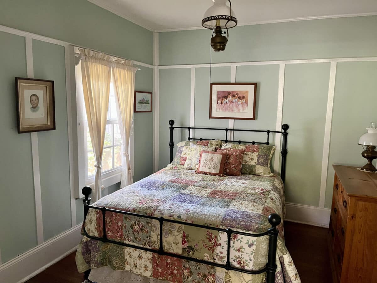 Alameda Post - a bed made up with a beautiful quilt with antique furniture and decor in the room