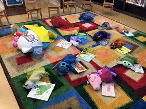 Alameda Post - stuffed animals lay scattered across a colorful rug looking like they have all fallen asleep reading books