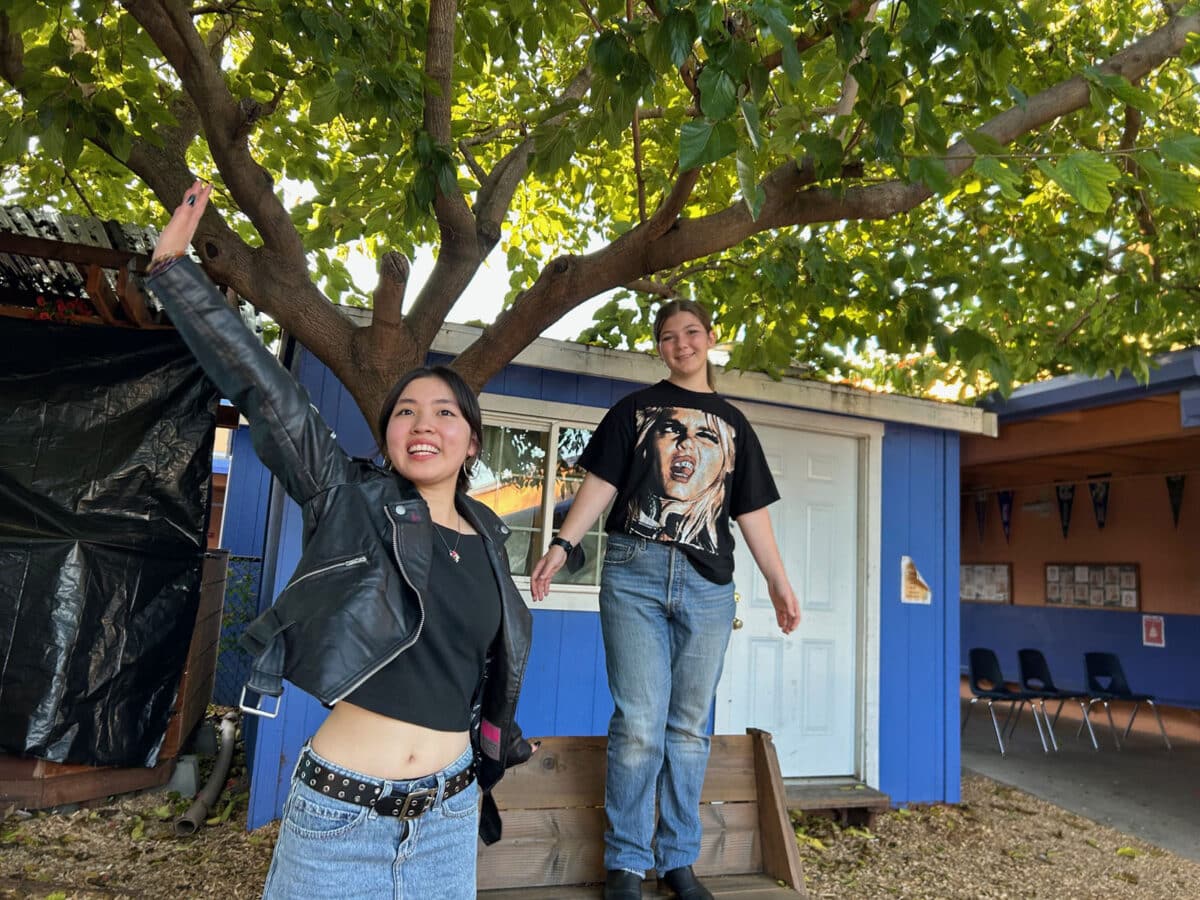 Alameda Post - Two high schoolers wave to the camera. One stands on a bench.