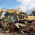 Alameda Post - the site at 2413 Buena Vista as a pile of timber. Heavy machinery and workers move around the demolished home
