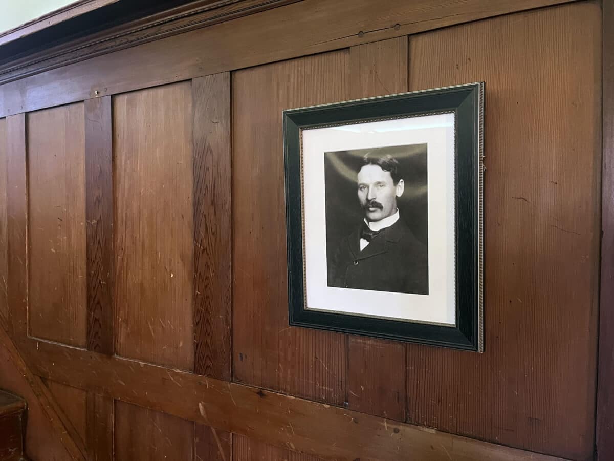 Alameda Post - A framed black and white portrait hangs on a wood paneled wall. 