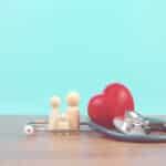 Alameda Post - a stock healthcare image of a small toy family surrounded by a stethoscope and heart