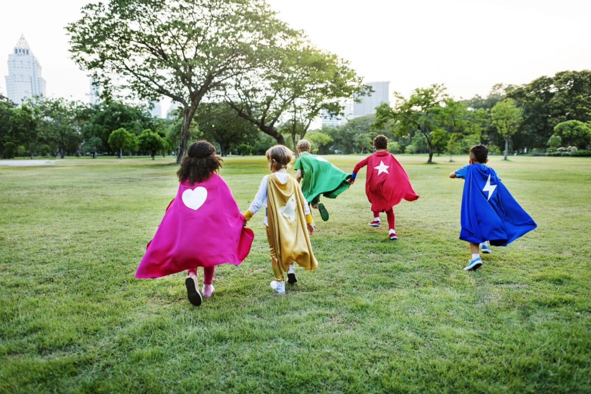 Alameda Post - Four children in superhero capes run in a park