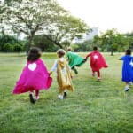 Alameda Post - Four children in superhero capes run in a park