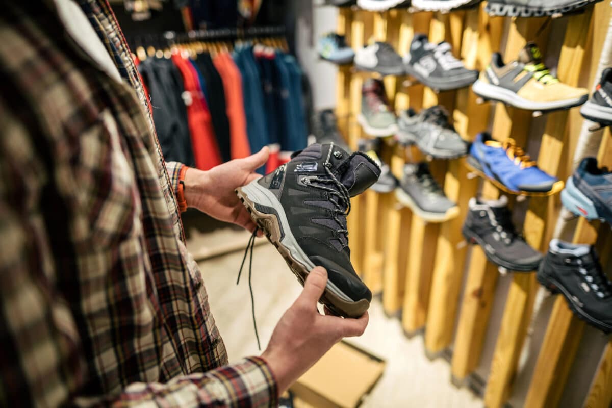 Alameda Post - A man holds a hiking shoe in a shoe store.