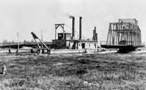 Alameda Post - a black and white photo of a dredge working on the waters around Alameda