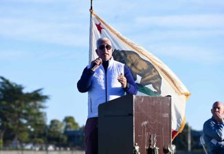 Alameda Post - Superintendent Pasquale Scuderi speaks into a microphone behind a podium outdoors at the new Enincal field.