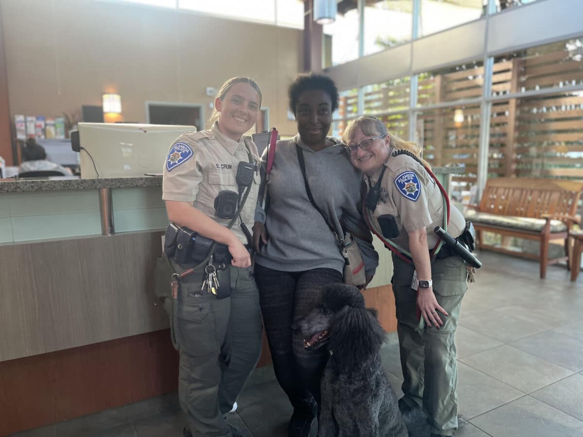 Alameda Post - a photo of two animal control officers and a citizen with a freshly groomed poodle. 