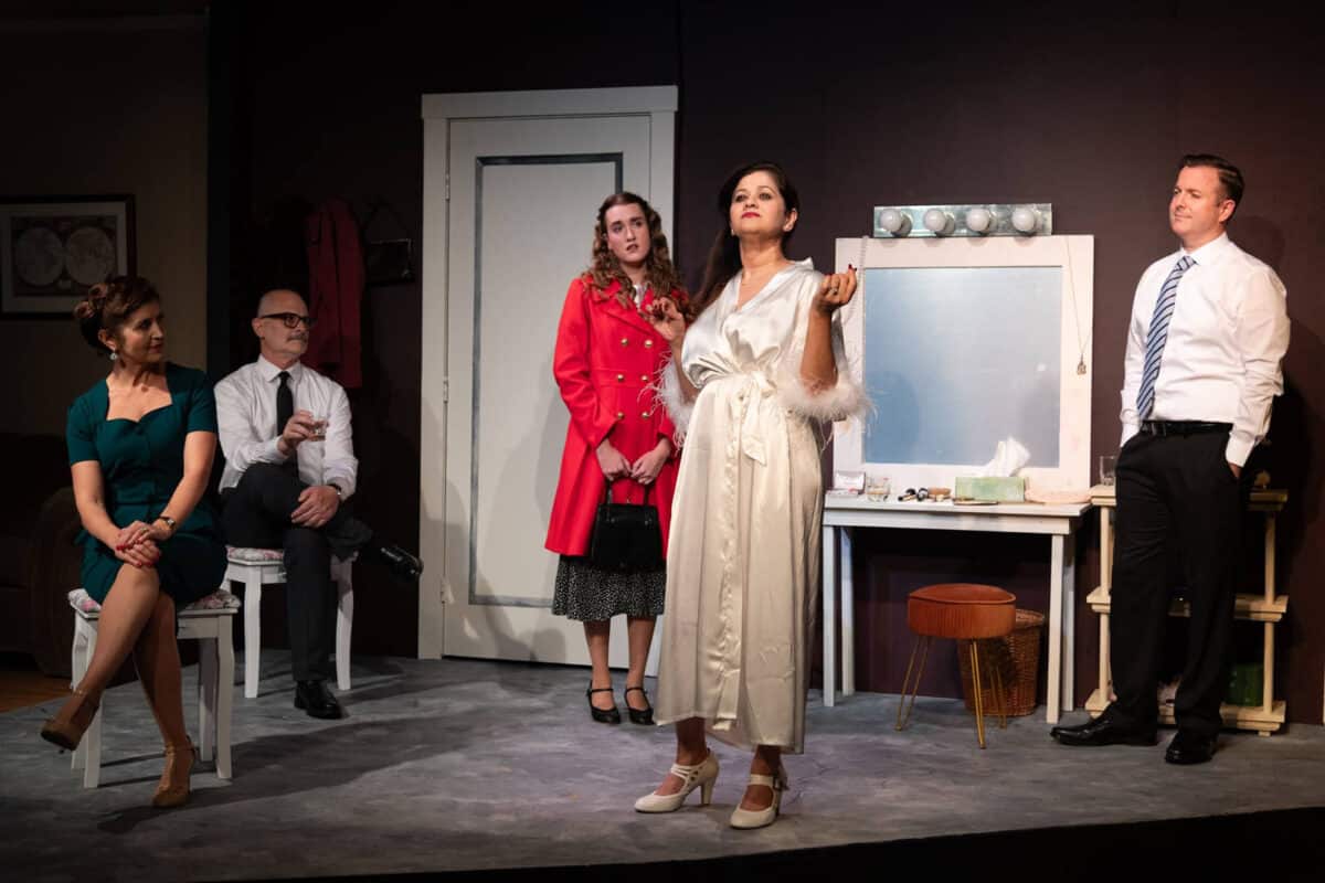 Alameda Post - Actors onstage perform The Wisdom of Eve. Actors stand in a dressing room while one woman in a white robe takes center stage.