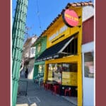 Alameda Post - the outside of Mango and Mint is bright yellow with red metal chairs and tables.