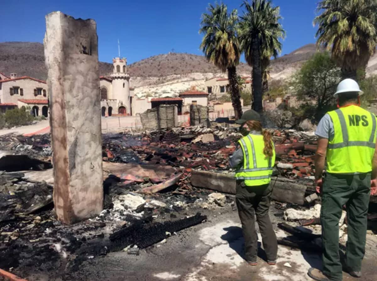 Alameda Post - park employees stand and look at the charred remains of a building near Scotty's Castle