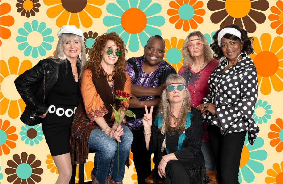 Alameda Post - A group photo of six woman in 60x style clothing in front of a flower background.