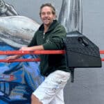 Alameda Post - Glenn Case smiles from scaffolding by a mural