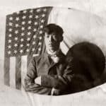 Alameda Post - a black and white photo of a man in front of an American flag