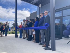 Alameda Post - A line of people stand and smile at the ribbon cutting for the new Transportation Technology Center.
