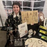 Alameda Post - A vendor at Queer Canvas smiles at their table of jewelry.
