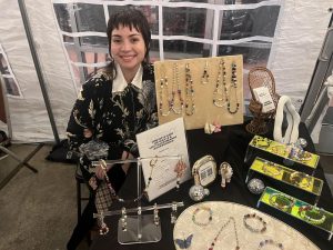 Alameda Post - A vendor at Queer Canvas smiles at their table of jewelry.
