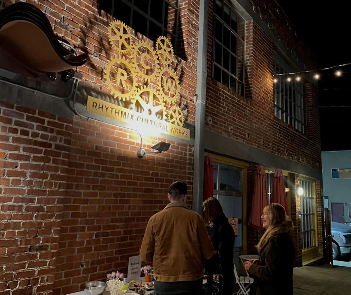 Alameda Post - Visitors stand outside of Rhythmix Cultural Works beneath their sign and gather around a welcome table. 