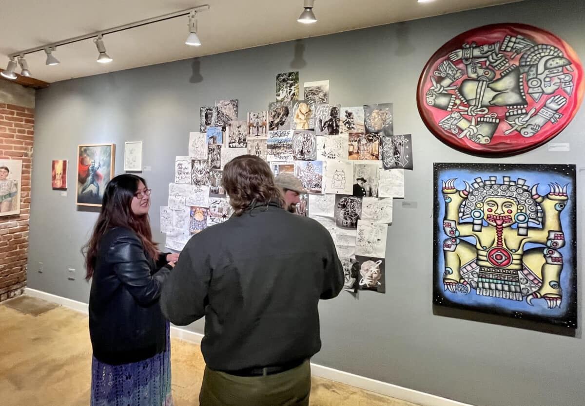 Alameda Post - Two visitors chat and look at a gallery wall at the "Art Comes From Art, Comes From Art" exhibit