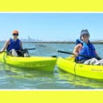 Alameda Post - two women in kayaks float in Ballena Bay with San Francisco in the distance on a Sea Trek tour
