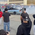 Alameda Post - people cather around a car with their phones out an an Alameda Point sideshow