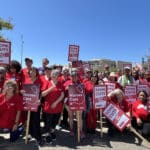 Alameda Post - nurses wearing pink and carrying signs pose during a protest of Alameda Hospital's decision to get rid of surgery