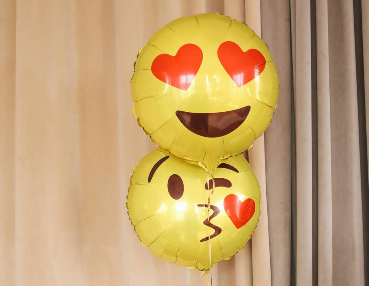 Alameda Post- photo of two emoji balloons, the first is a smile with heart eyes, the second is a kissy-face emoji balloon. 