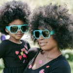 Alameda Post - a parent holds their child. They both wear matching sunglasses