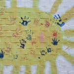 Alameda Post - a sun painted on a wall with handprints
