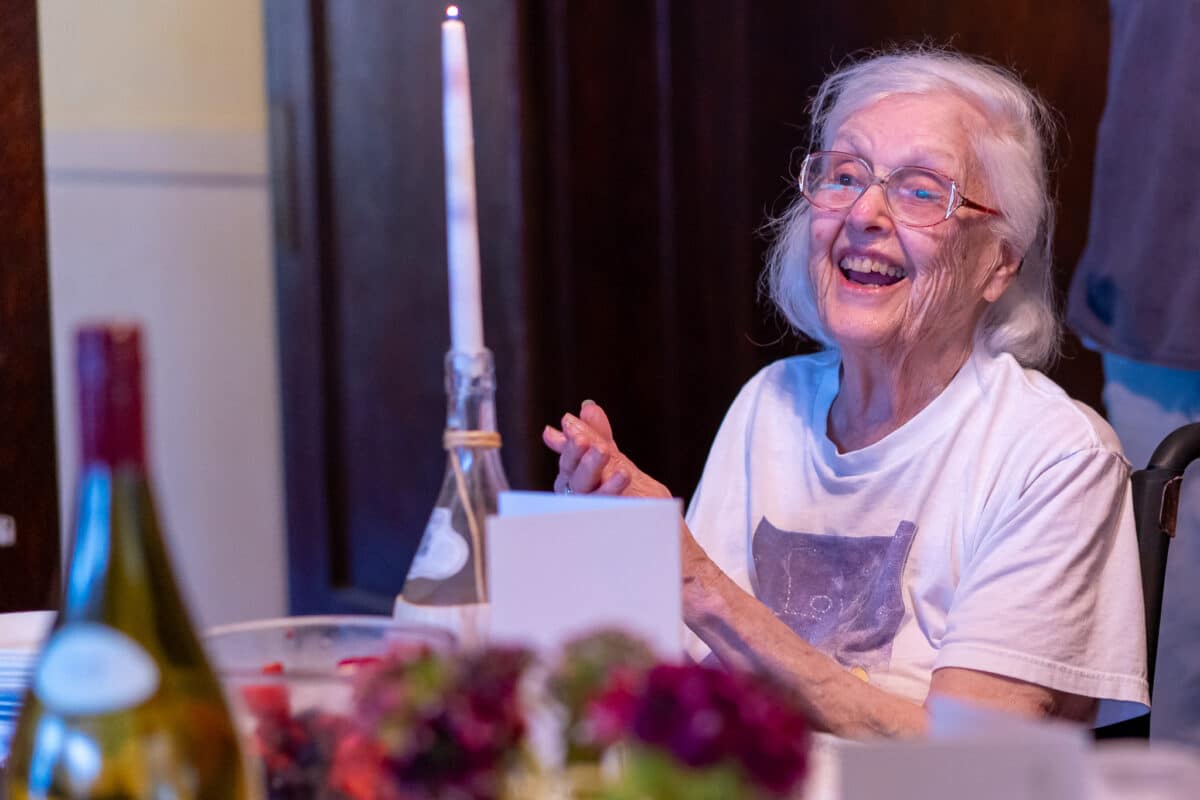 Alameda Post - An older Patricia Ferris Millosovich with white hair smiles at the dinner table. 